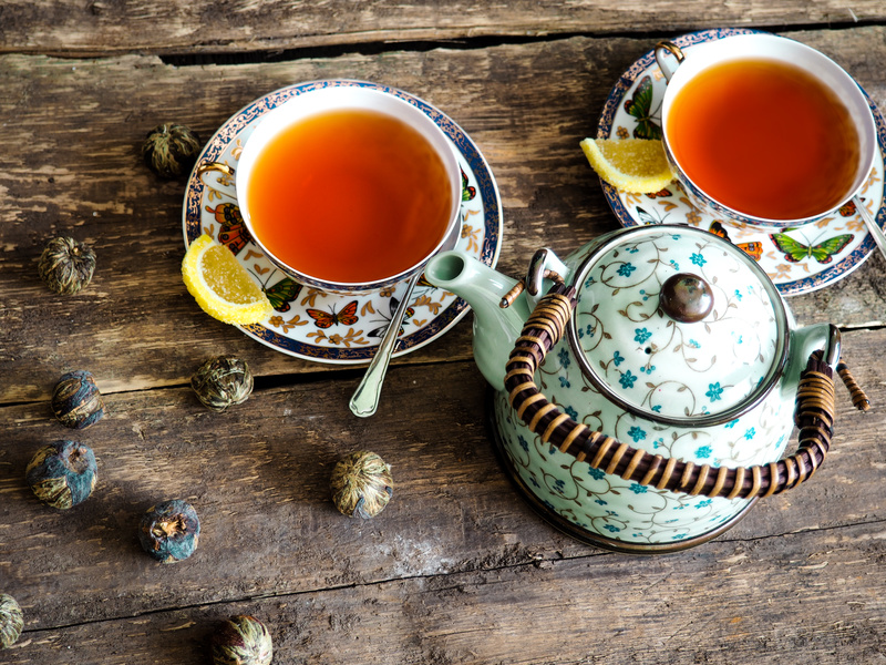 Teapot and glass cups with tea against wooden background